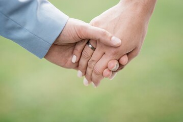 Closeup of the bride and groom holding hands with rings at a wedding
