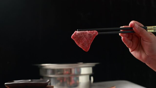 Woman hand using chopsticks pinking up wagyu beef. Grilled japanese premium wagyu beef Sirloin steak