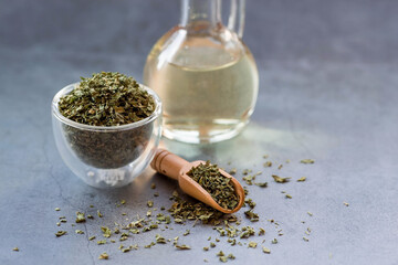 Fragrant spices. Dried parsley and a bottle of oil on a gray background. Free space.