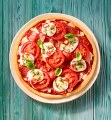 Pizza mit Tomaten und Mozzarella auf mint farbenem Fond