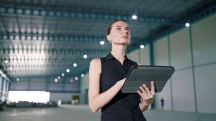 Caucasian woman manager using tablet for work and recheck the orderliness or stock of product in the factory or warehouse