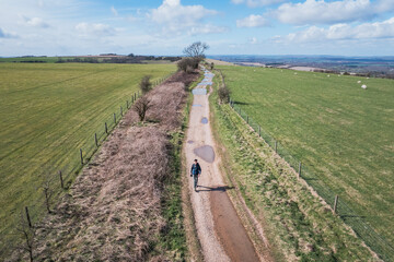 lone hiker walking along footpath in the countryside of Kintbury, Berkshire, England