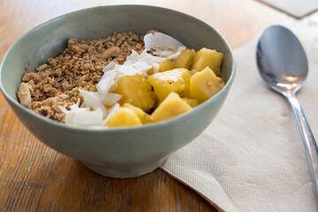 View of typical brazilian açaí bowl with cereals, coconut and pineapple. Healthy breakfast