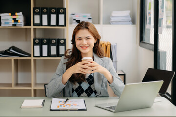 Asian businesswoman working in the office with working notepad, tablet and laptop documents .