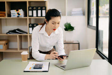 Young beautiful woman typing on tablet and laptop while sitting at the working wooden table office.