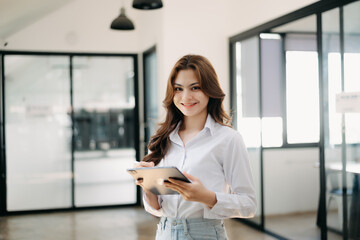Obraz premium Confident business expert attractive smiling young woman holding digital tablet on desk in creative office..