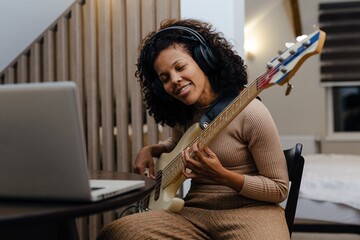 Girl playing jazz music. Woman musician with bass guitar at home