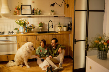 Young couple sit relaxed together with a cute dog on kitchen at home. Home coziness and domestic lifestyle concept