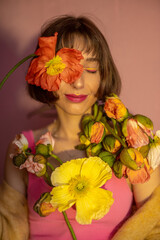 Portrait of a young woman with island poppy cutted flowers on pink background. Concept of beauty and summer