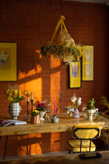 Beautiful dining table decorated with flowers in living room with brick wall and pictures behind