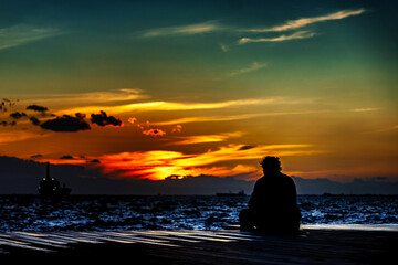 Naklejka na ściany i meble Mensch bei Sonnenuntergang auf Pier