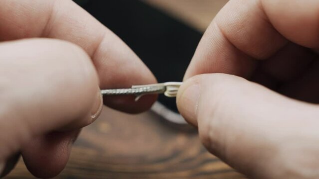 A man holds an electric wire with damaged insulation in his hands, examines it. Close-up.