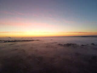 Fototapeta na wymiar Cloud inversion covering an industrial setting during sunrise