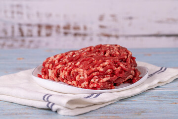 Beef minced on the plate. Fresh ground beef on wood background.