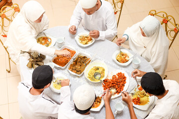 Top view of family togetherness at eid mubarak moment. Enjoying ketupat lebaran and special food dishes at dining room. 