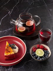 Fototapeta na wymiar tea with lemon in a teapot with cheesecake and berries