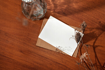 Aesthetic boho flatlay, blank paper card mockup with copy space and dried flowers on wooden table background, minimalist neutral business, brand template