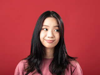 A close-up portrait of a young Indonesian (Asian) woman wearing a pink shirt. Isolated with a red background