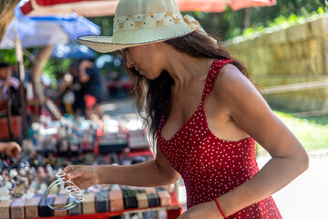 Tourist buying souvenirs at a street stall selling costume jewelry and gifts at the amazing site of the Kulkulcan pyramid in Chichen Itza, also home to the temple of the Yucatan Peninsula. - obrazy, fototapety, plakaty