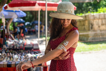 Tourist buying a costume jewelry bracelet and souvenirs at a street stall selling costume jewelry and gifts at the amazing site of the Kulkulcan pyramid at Chichen Itza. - obrazy, fototapety, plakaty