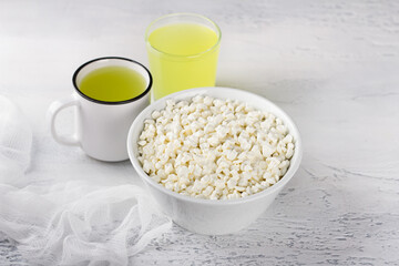 Fresh homemade grained cottage cheese and whey on a light blue background