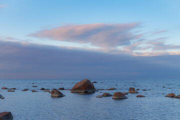 Boulders on the shore of the Baltic sea. Cloudy sunset.