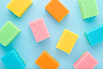 New colorful dry sponges on light blue table background. Pastel color. Closeup. Pattern of cleaning...