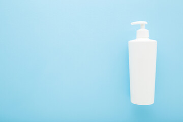 White big plastic pump bottle on light blue table background. Pastel color. Care about clean and soft body skin. Daily beauty product. Closeup. Empty place for text or logo. Top down view.