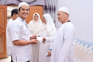 Fototapeta premium Smiling young man having present from father at eid mubarak moment. 