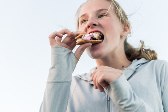 teen girl enjoying smores made with chocolate, marshmallow and biscuit
