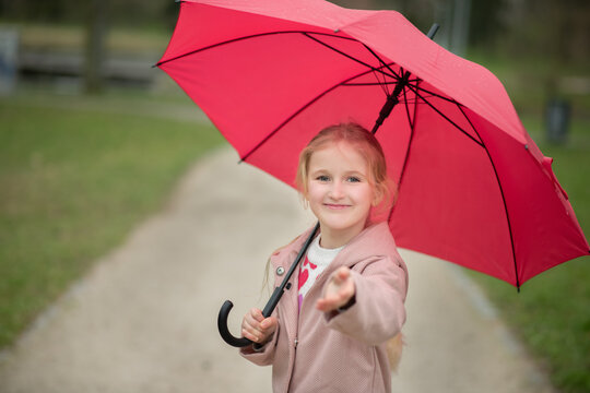 girl under a red umbrella. walks in the open air
