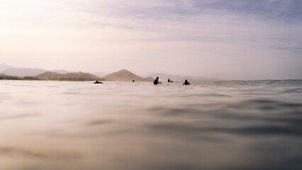 View of surfers group floating in the Pacific ocean near coast waiting for the wave, Baja California Sur, Mexico.
