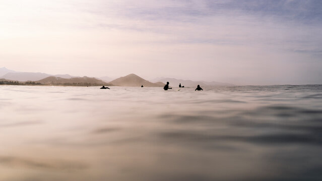 View of surfers group floating in the Pacific ocean near coast waiting for the wave, Baja California Sur, Mexico.