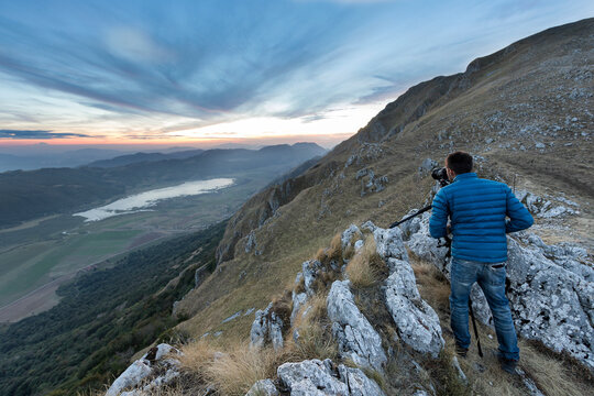 View of a person standing on the rocks taking photos from mountain top at Matese lake, Campania, Italy.