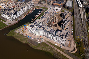 Aerial view of luxury Kade Zuid apartment complex construction at riverbank of river IJssel between train tracks and recreational port. 