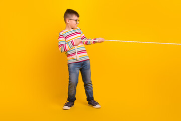 Full profile side photo of sweet kid boy playing outdoors pull string isolated on vibrant color background