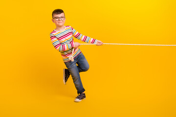 Full body photo of kid boy have weekend free time play active sport game tug war isolated on bright color background