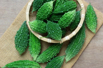 close up view of bitter gourd fruit on wooden table, food and herbal plant concept.