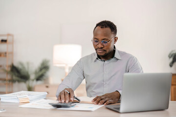 Fototapeta na wymiar Portrait of handsome African black young business man working on laptop at office desk.