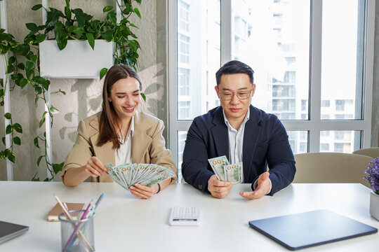 Man And Woman Sitting In Office, Holding Money At Hands. Gender Pay Gap, Unequal Salary Concept