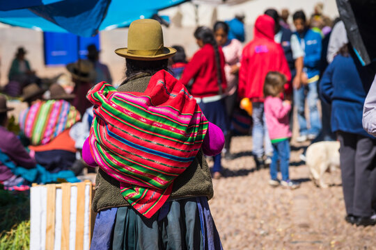 Peruvian woman carrying colorful bag on her back, Pisaq market, Sacred Valley, Cusco, Peru