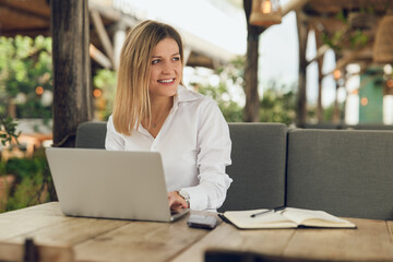 Smiling female freelancer working remotely in outdoor cafeteria