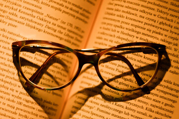 An open book and glasses lying on it isolated with warm light falling on it.