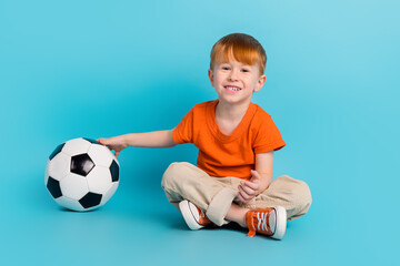 Photo of charming positive cute boy sitting floor enjoy hobby like football watching final league isolated on cyan color background