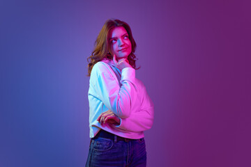 Fantasy inside head. Pretty young girl in white hoodie posing with thoughtful dreamy face against gradient blue purple background in neon light. Emotions, youth, lifestyle, facial expression concept