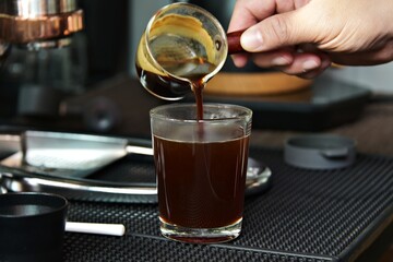 brewing espresso full of crema on top, black coffee in glass cup