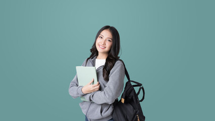 Young Asian girl college student with tablet and backpack isolated over teal background