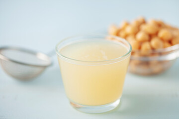 Composition with glass of aquafaba and chickpeas on blue table. Vegan meals  concept