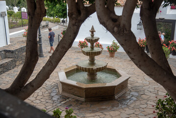 Captura de detalle de una fuente de agua en medio de una plaza y gente caminando alrededor de ella...