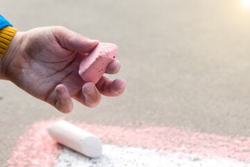 the child holds colored chalk in his hand